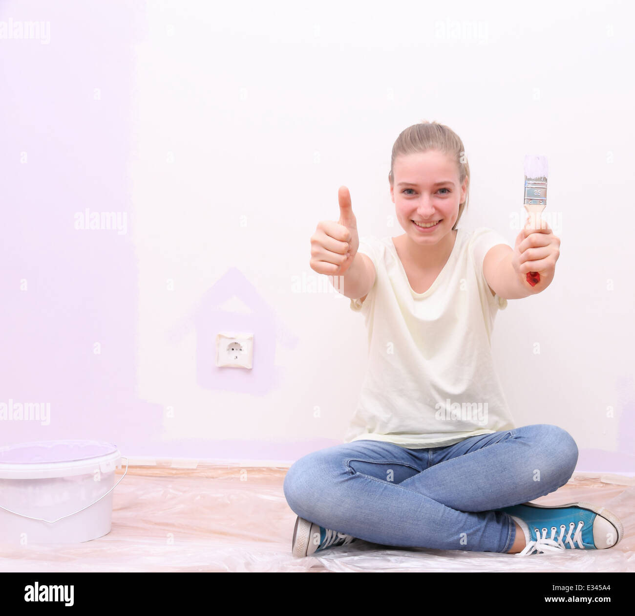 Mädchen tun OK Schild am Haus Renovierung in lila Farbe Stockfoto