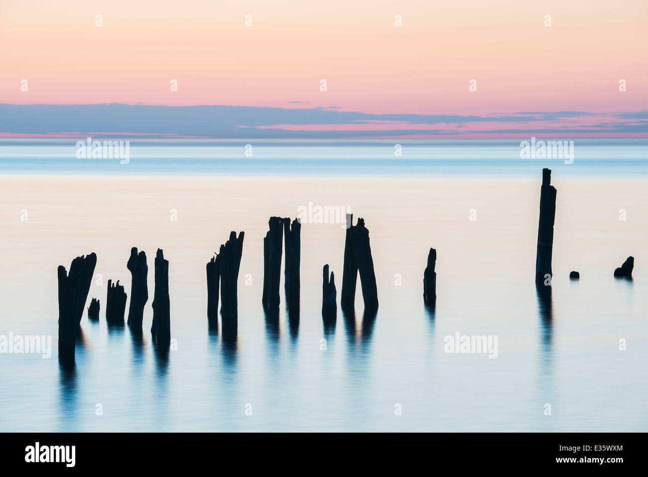 Schattenhafte Figuren, Reste der Dock Pilings halten Sie ruhig in den großen See Lake Huron, Michigan, USA. Stockfoto