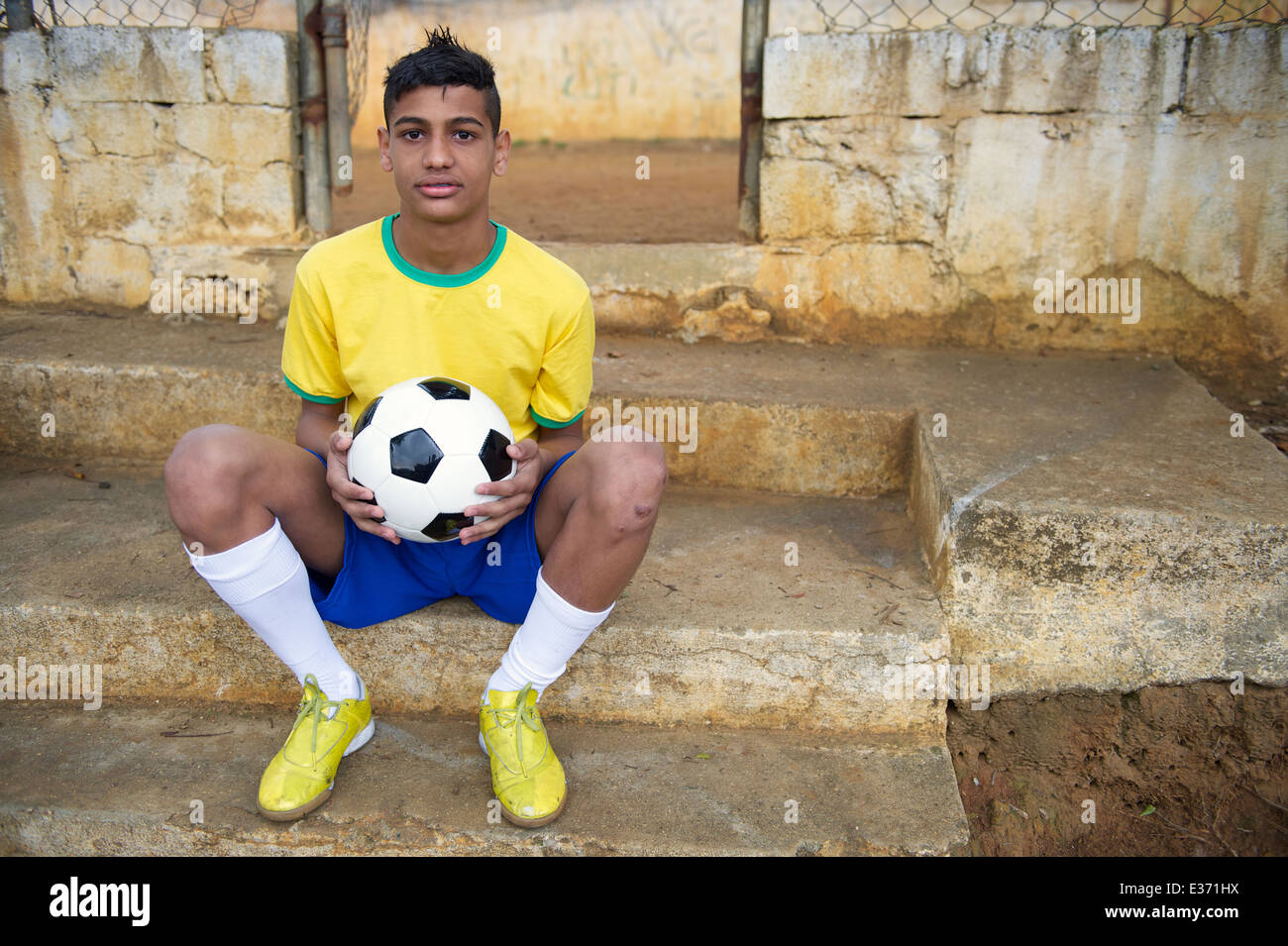 Junge brasilianische Fußballspieler, Fußball Ball sitzen im Freien in seiner Nachbarschaft favela Stockfoto