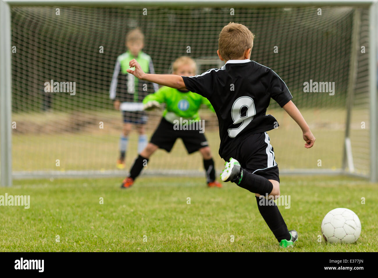Torwart und Strafe Kicker in der Mitte einen Elfmeter während ein Jugend-Fußballspiel. Schwerpunkt ist der Kicker. Stockfoto
