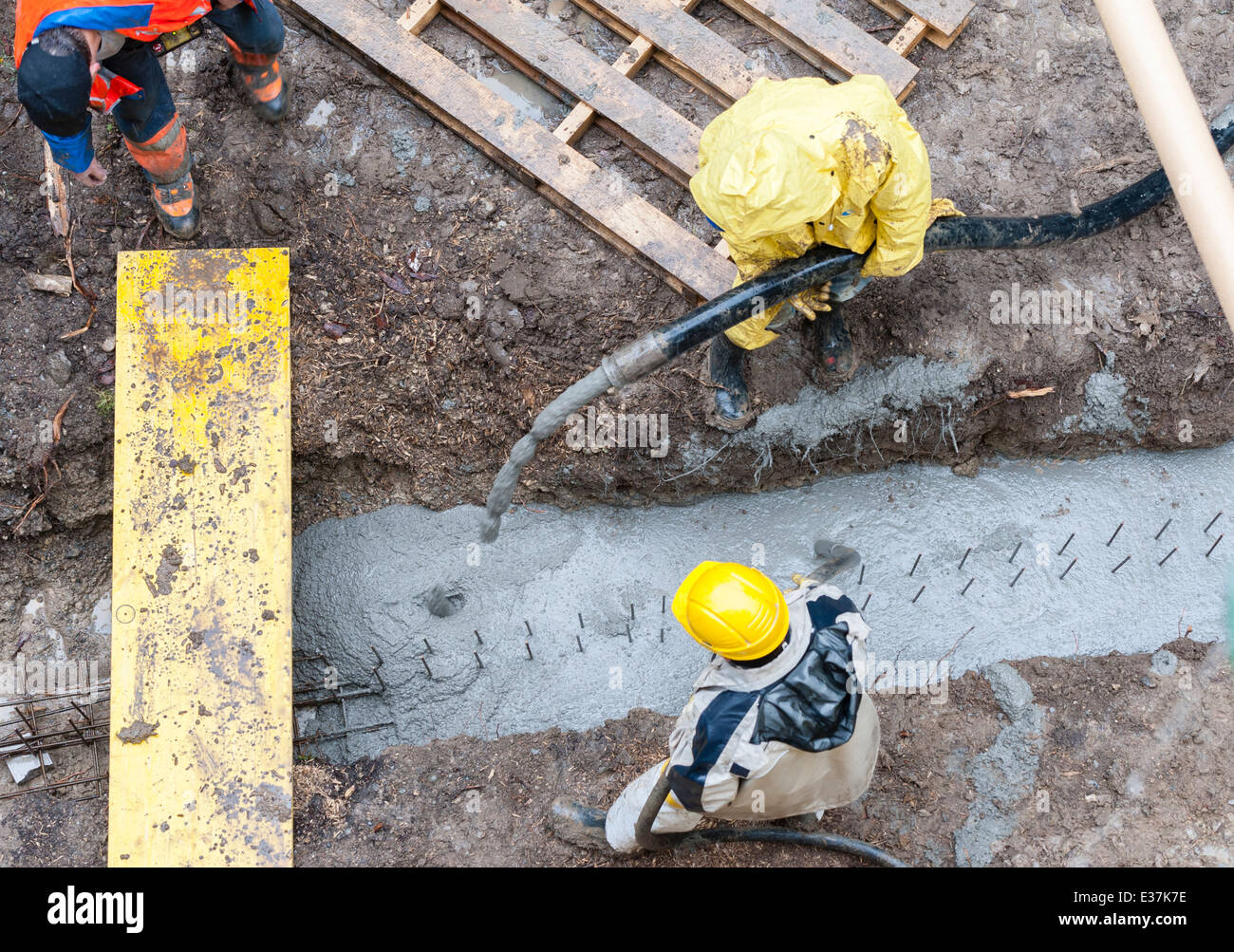 Bauarbeiter Gießen Sie Beton in einen Graben. Regenwetter. Vogelperspektive. Stockfoto