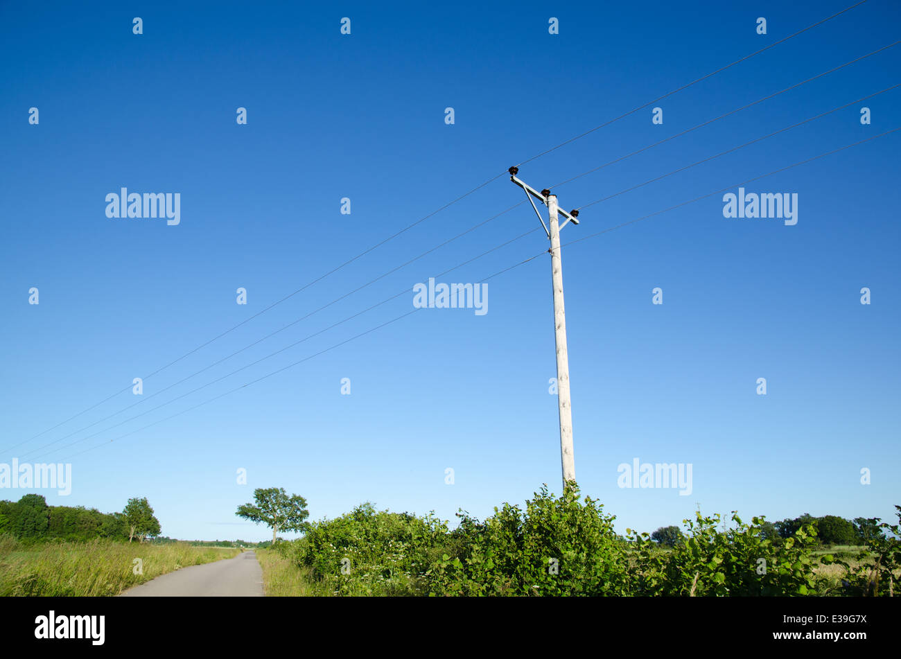 Mast mit Powerlines von einer Landstraße bei blue sky Stockfoto