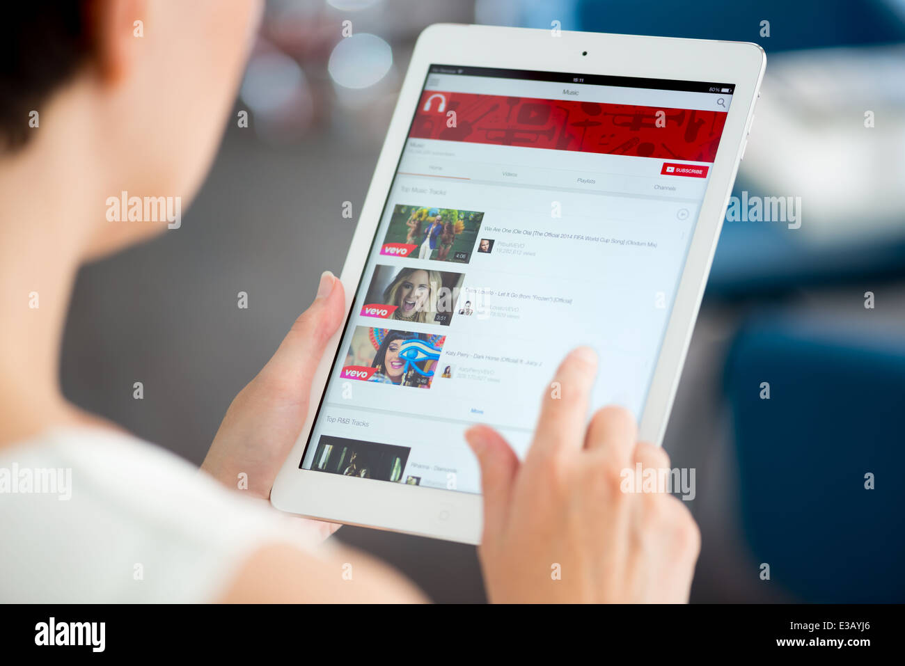 Frau hält ein nagelneues Apple iPad Air und auf der Suche auf YouTube Musik-Wiedergabeliste auf einem Bildschirm Stockfoto
