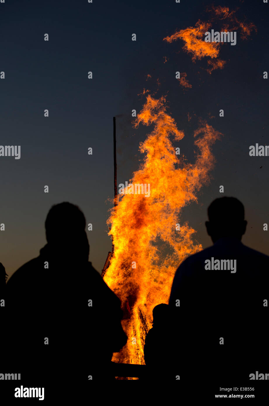 Menschen auf dem 1.243 m-Kandel-Berg in der Region Schwarzwald Silhouette gegen den Himmel, wie sie sehen, eine große Sommer-Sonnenwende Feuer auf der Bergspitze zur Feier des Jahres am längsten beleuchteten Tag, in der Nähe von Waldkirch, Deutschland, spät 21. Juni 2014. Foto: Patrick Seeger/dpa Stockfoto