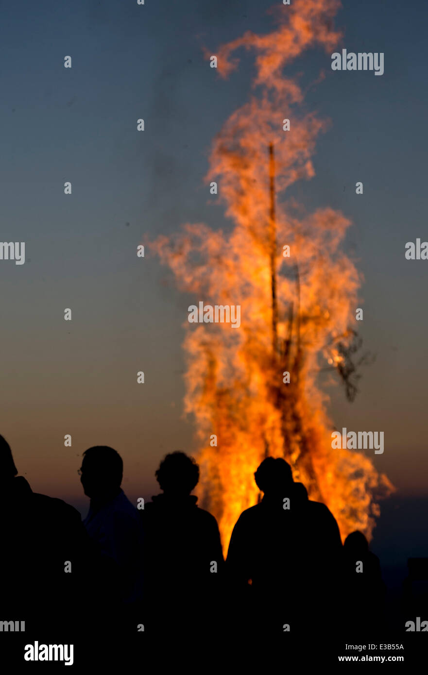 Menschen auf dem 1.243 m-Kandel-Berg in der Region Schwarzwald Silhouette gegen den Himmel, wie sie sehen, eine große Sommer-Sonnenwende Feuer auf der Bergspitze zur Feier des Jahres am längsten beleuchteten Tag, in der Nähe von Waldkirch, Deutschland, spät 21. Juni 2014. Foto: Patrick Seeger/dpa Stockfoto