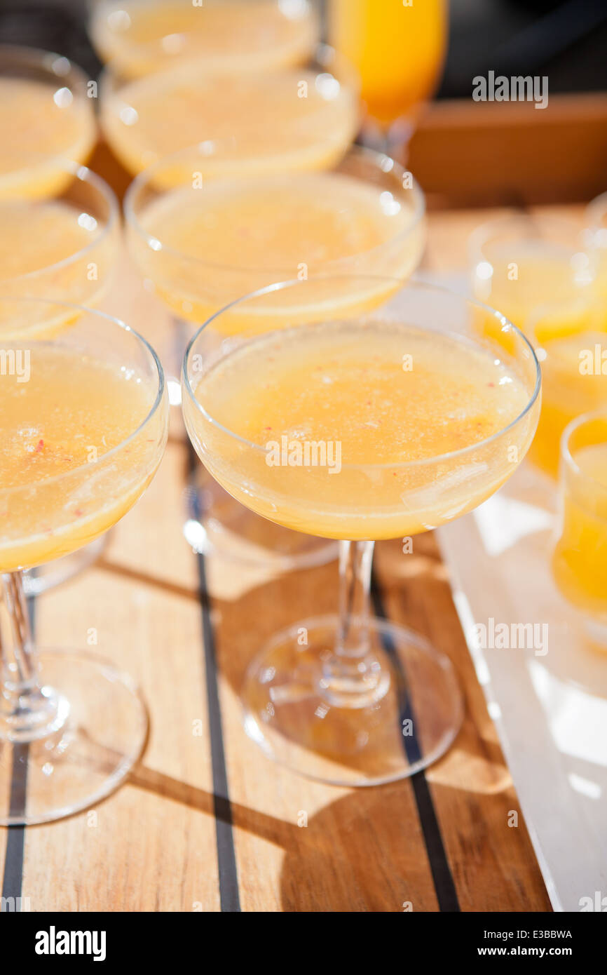 Nahaufnahme der Gläser Orangensaft in Reihen auf Holz Serviertablett auf Outdoor-Party im Sonnenlicht Stockfoto