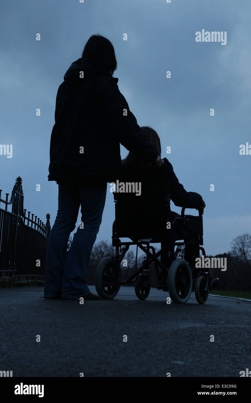 Frau treibt ein junges Mädchen in einem Rollstuhl sitzt. Stockfoto