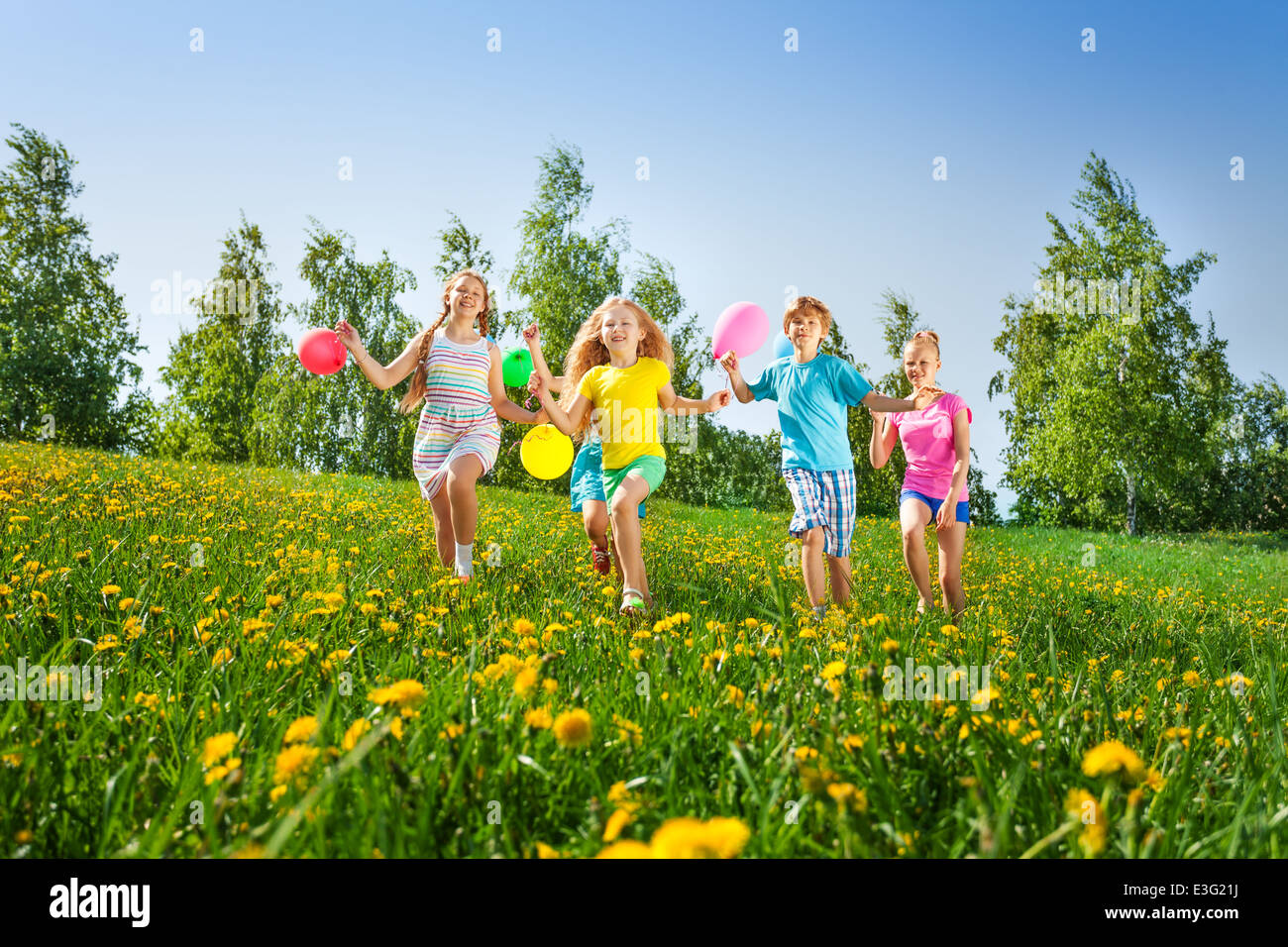 Glückliche Kinder laufen mit Luftballons im Sommer Stockfoto