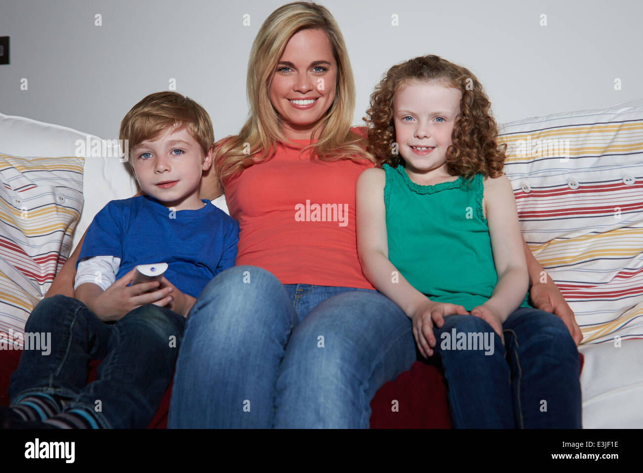 Mutter und Kinder sitzen auf dem Sofa vor dem Fernseher zusammen Stockfoto