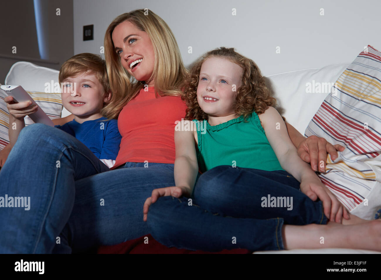 Mutter und Kinder sitzen auf dem Sofa vor dem Fernseher zusammen Stockfoto