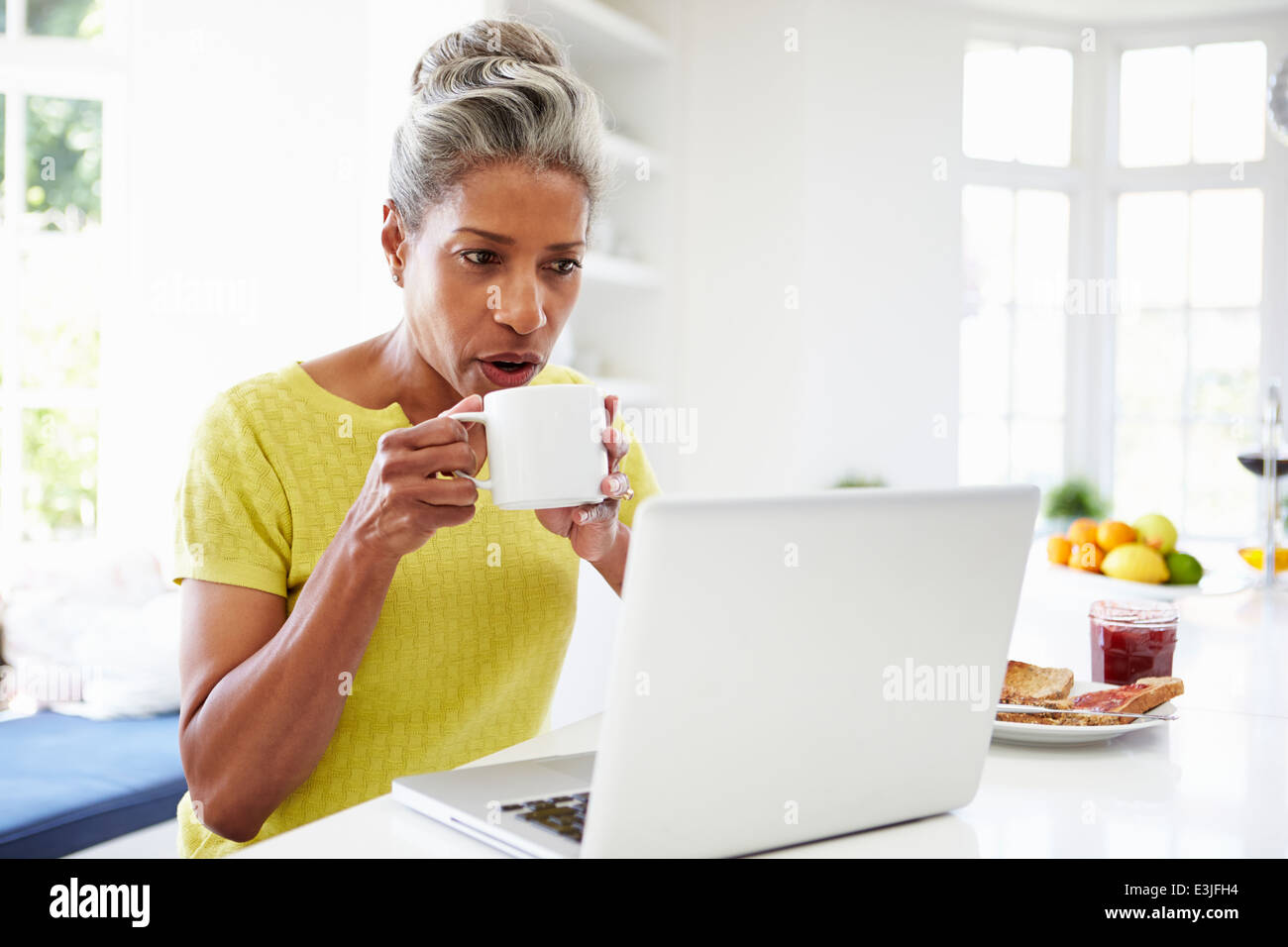 Afroamerikanische Frau mit Laptop In der Küche zu Hause Stockfoto