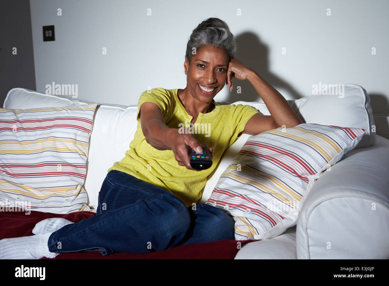 Reife afroamerikanische Frau auf dem Sofa vor dem Fernseher Stockfoto