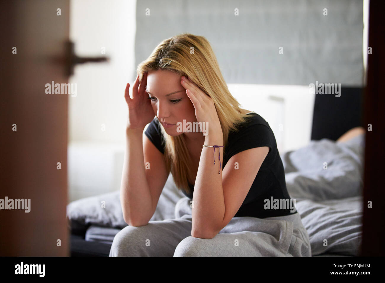 Traurige Teenager-Mädchen sitzen im Schlafzimmer während Freund schläft Stockfoto
