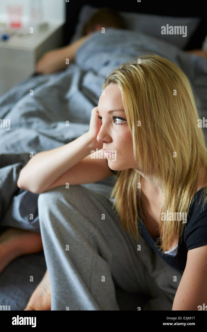 Traurige Teenager-Mädchen sitzen im Schlafzimmer während Freund schläft Stockfoto