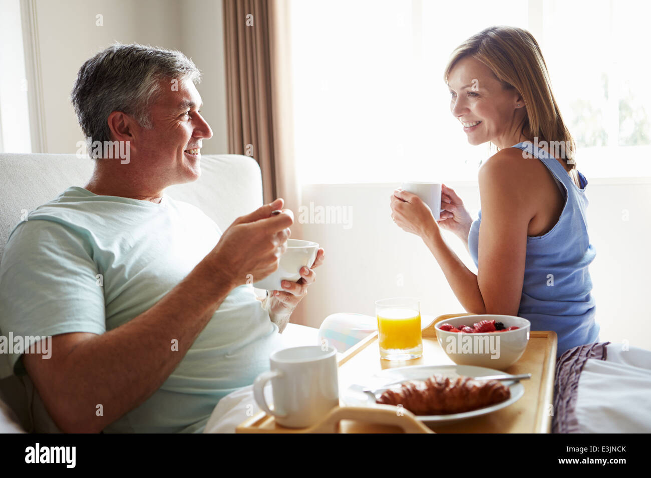 Frau bringt Mann das Frühstück im Bett auf Tablett Stockfoto