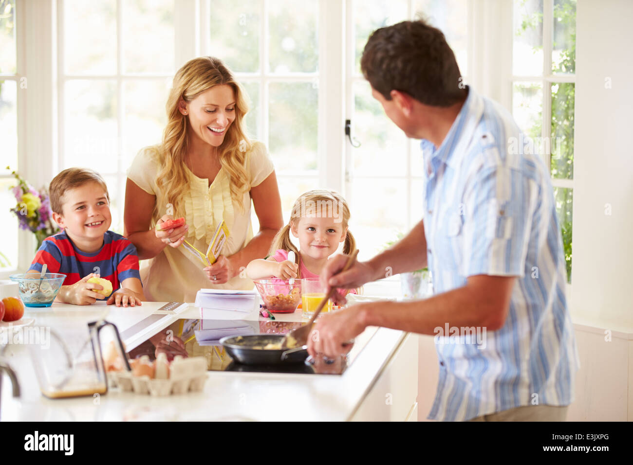Vater bereitet Frühstück mit der Familie In Küche Stockfoto