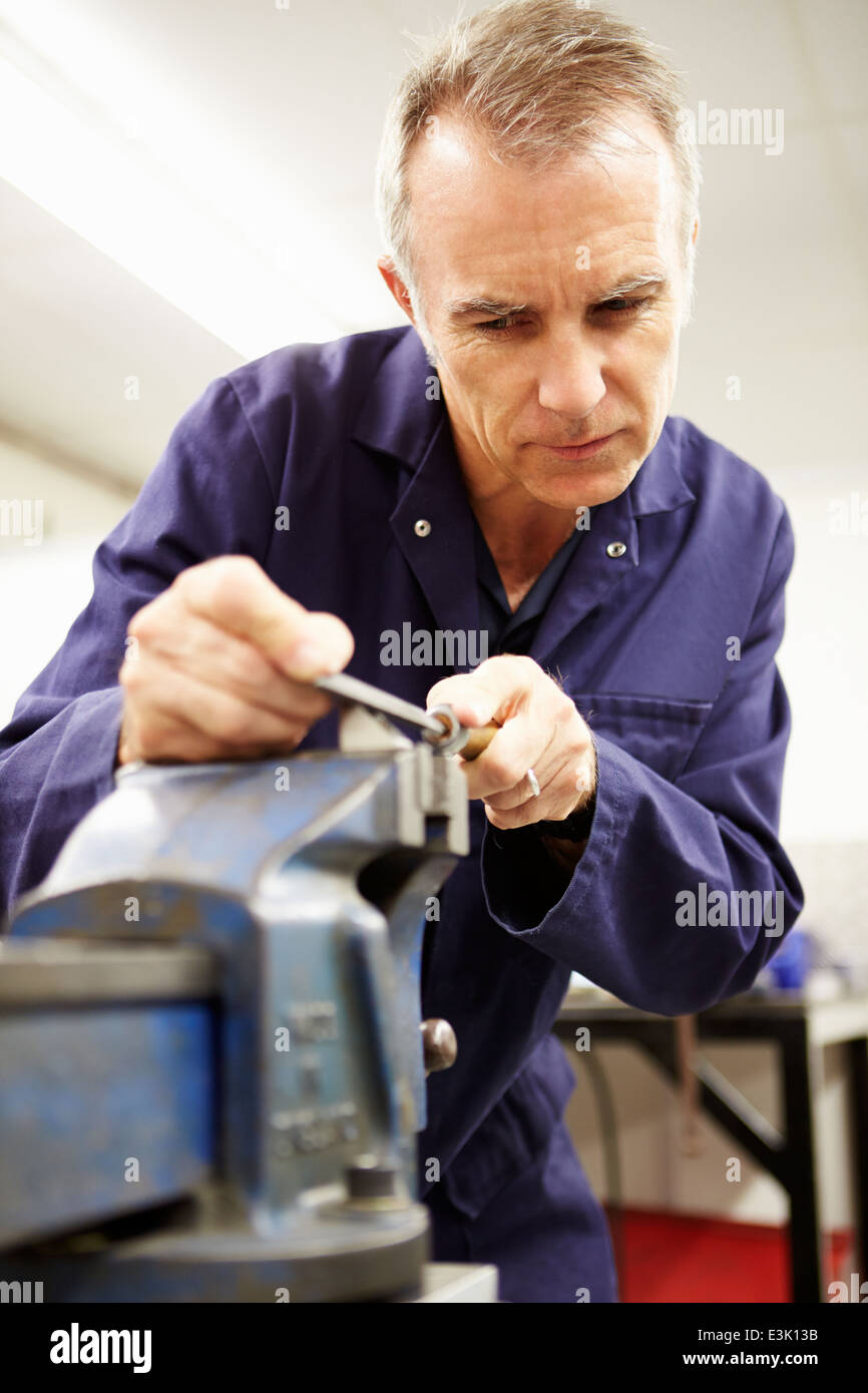 Ingenieur mit Metallfeile in Fabrikhalle Stockfoto