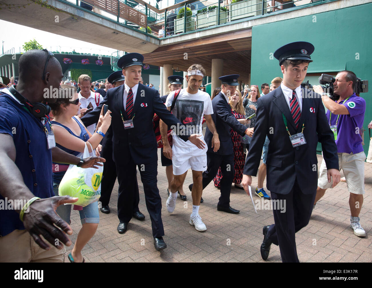 Wimbledon, London, UK, 24. Juni 2014. Bild zeigt Roger Federer (SUI) an Tag zwei der Wimbledon Tennis Championships 2014 wird begleitet von Sicherheit durch Zuschauer nach dem Aufwärmen auf Court Nr. 4 Kredit: Clickpics/Alamy Live News Stockfoto