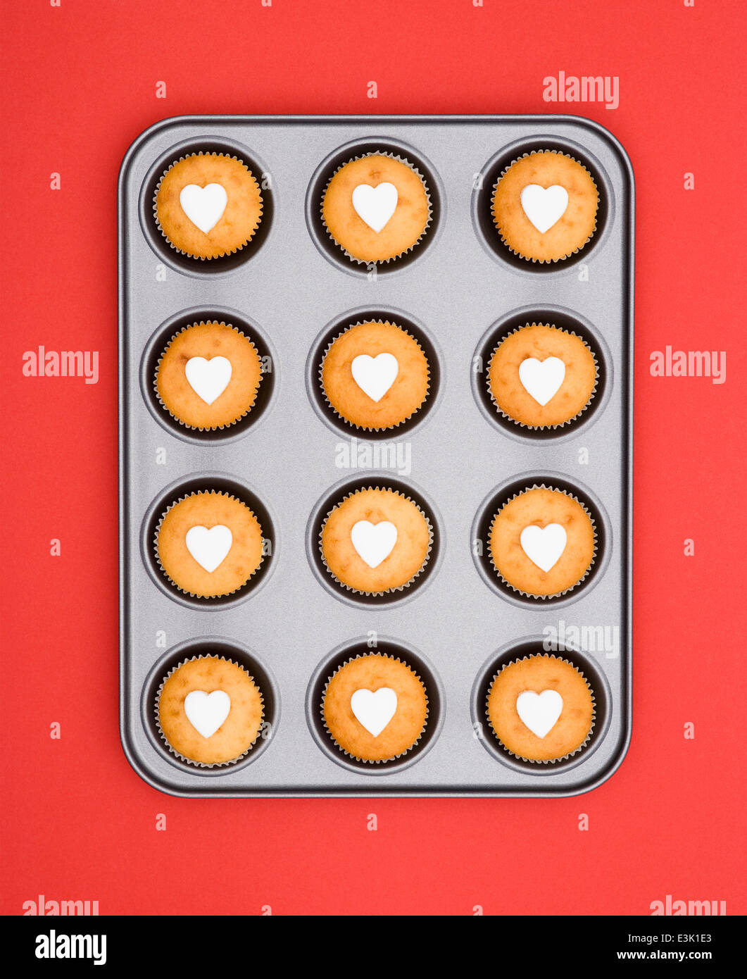 Feenkuchen, verziert mit Cut-out Fondant Vereisung Herzen, Backform auf einem roten Hintergrund. Stockfoto