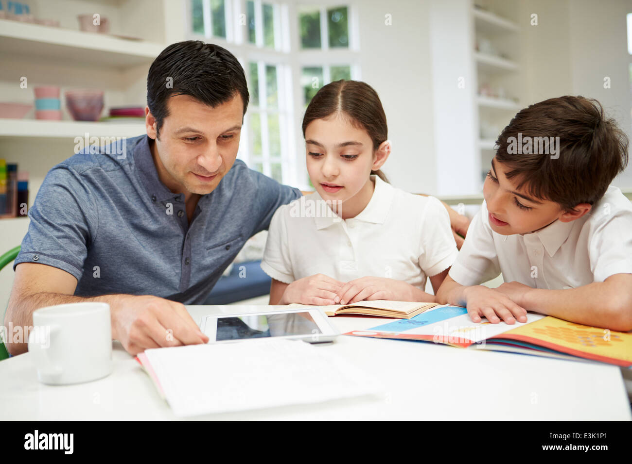 Vater hilft Kindern bei den Hausaufgaben mit Digital-Tablette Stockfoto