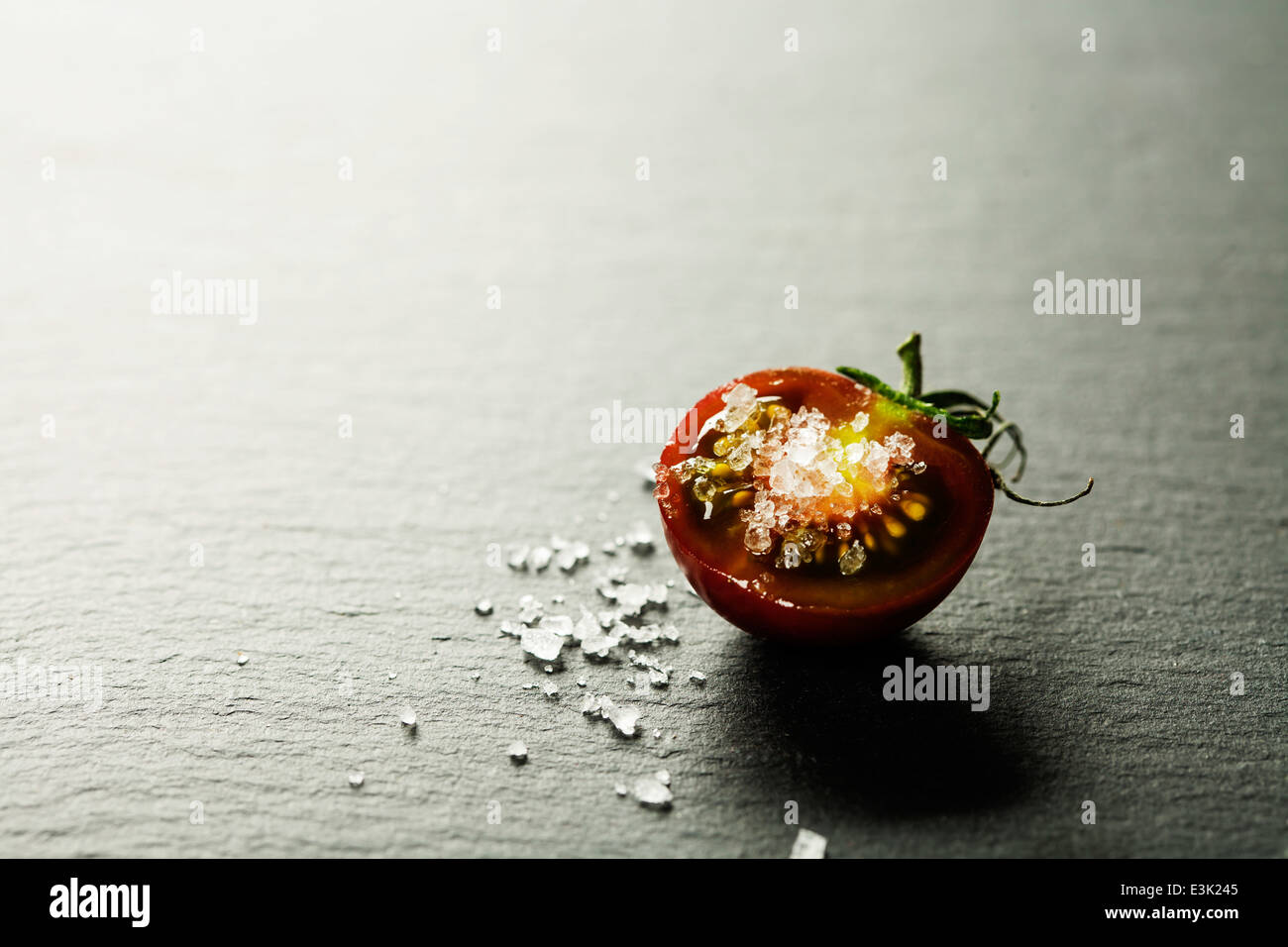 Frische Trauben Tomaten mit Salz für den Einsatz als kochen Zutaten mit halbierten Tomaten im Vordergrund mit Exemplar Stockfoto