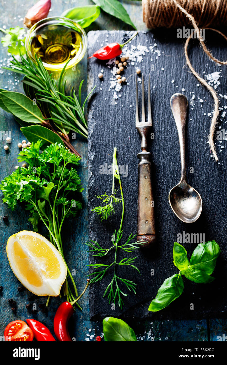 Essen-Hintergrund, mit Kräutern, Gewürzen, Olivenöl, Salz, Zitronen und Gemüse. Schiefer und Holz Hintergrund. Stockfoto