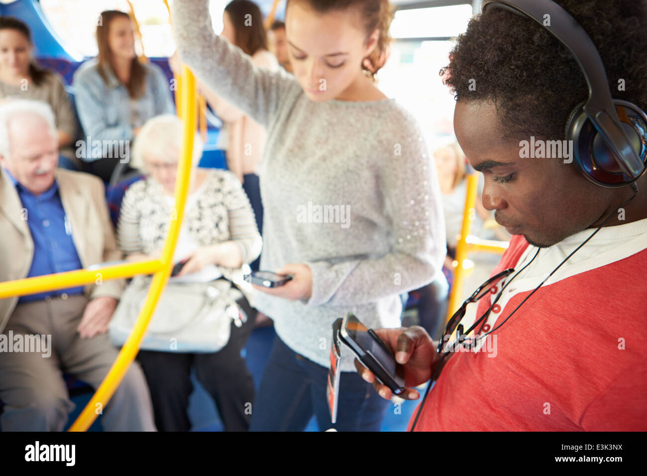 Passagiere, die mit mobilen Geräten auf dem Bus Stockfoto