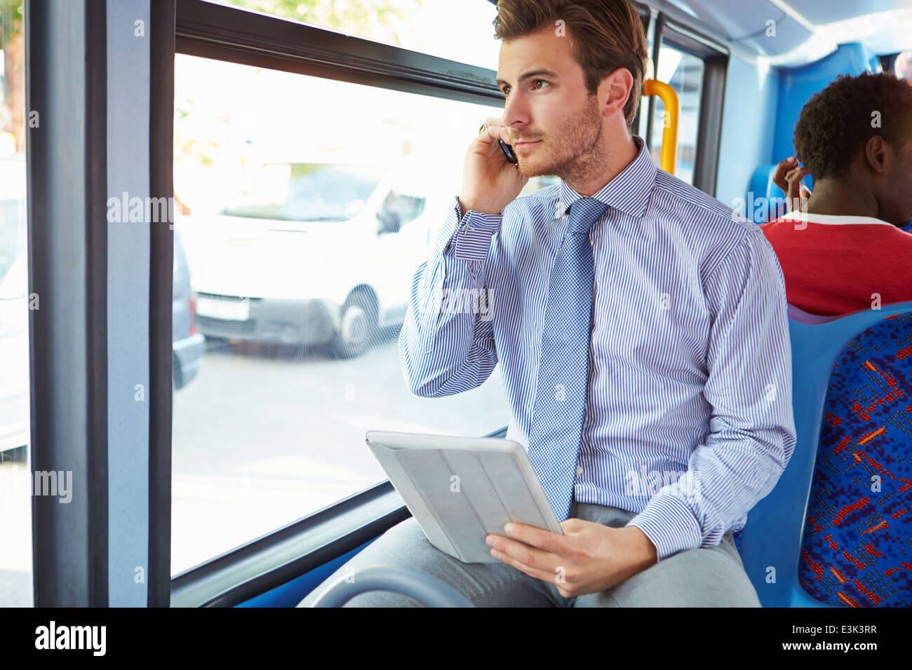 Geschäftsmann mit Handy und Digital-Tablette auf Bus Stockfoto