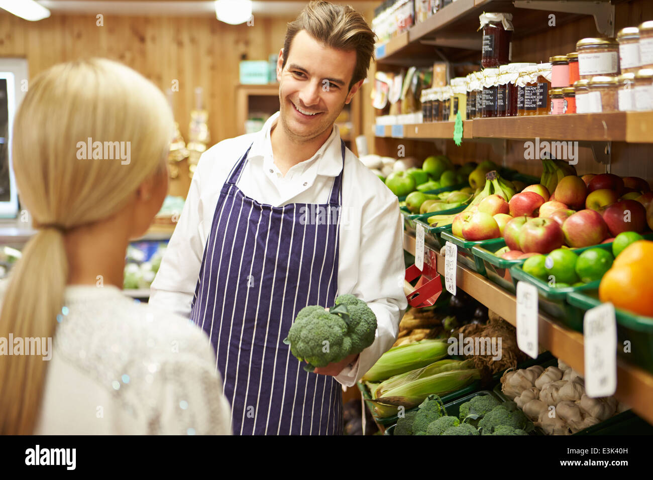 Assistent hilft Kunden bei Gemüsetheke Hofladen Stockfoto
