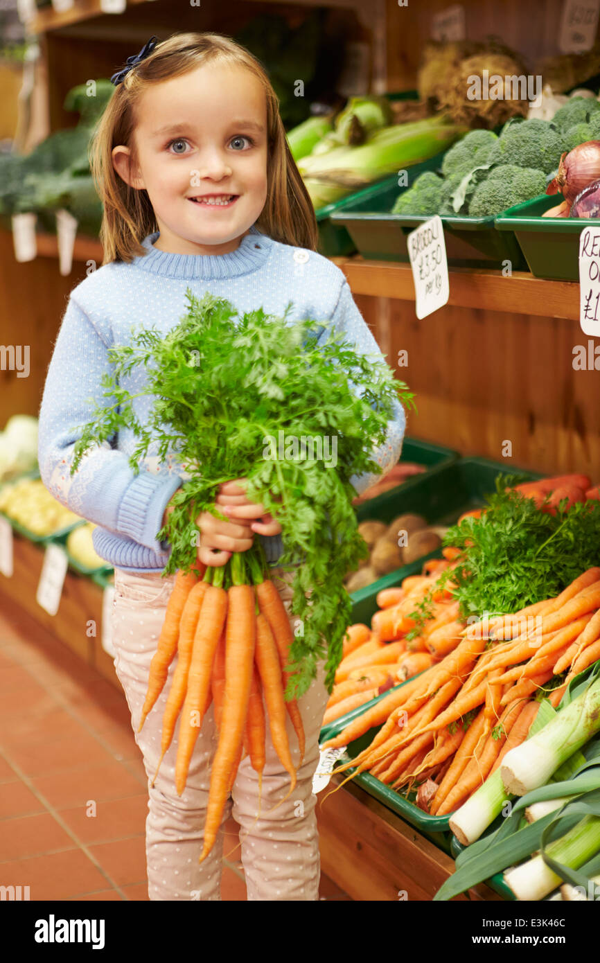 Junges Mädchen halten Bund Karotten im Hofladen Stockfoto