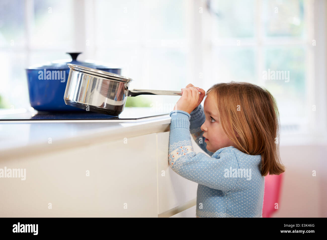 Junges Mädchen zu riskieren Unfall mit Pan In Küche Stockfoto