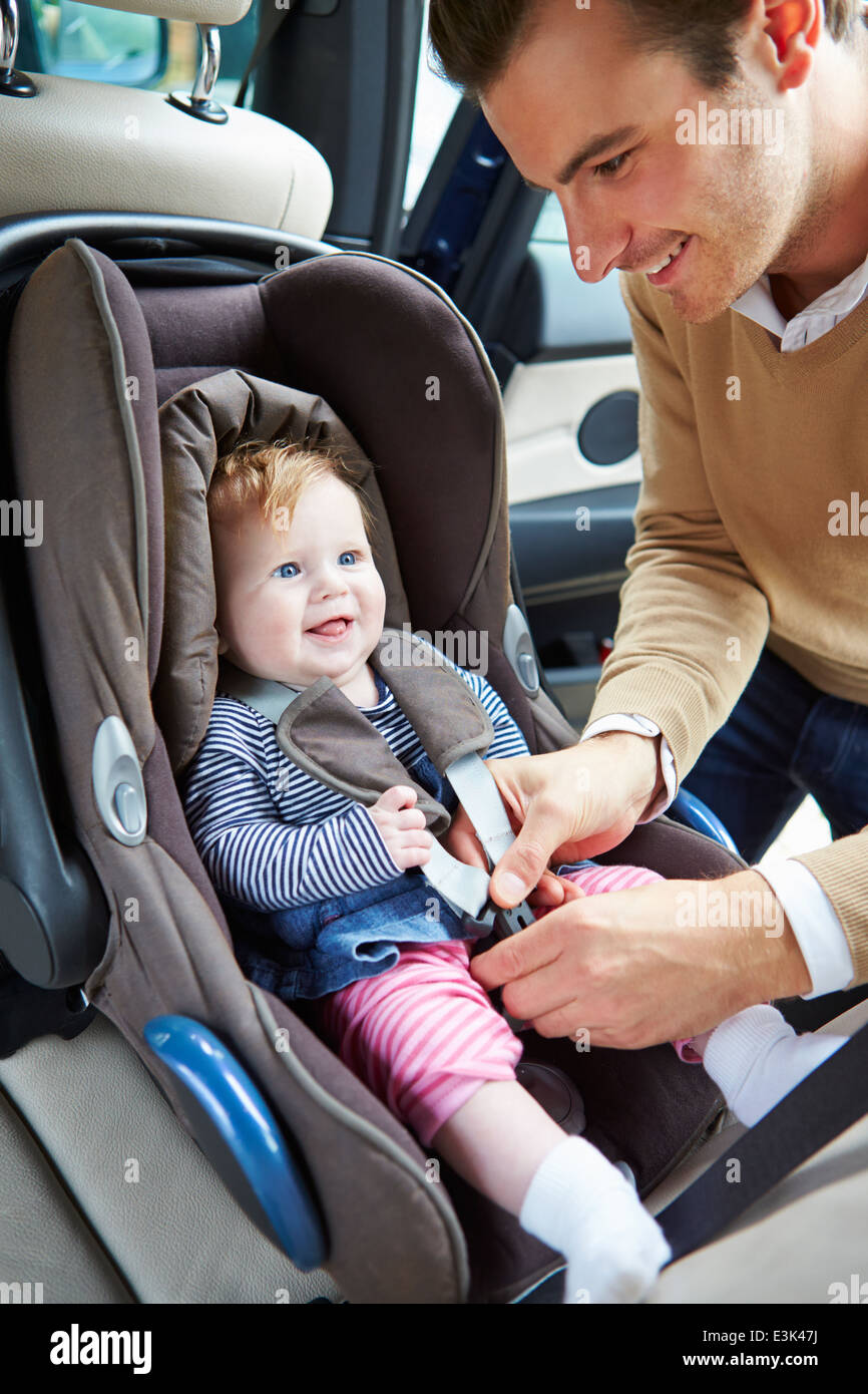 Vater Putting Baby in Autositz Stockfoto