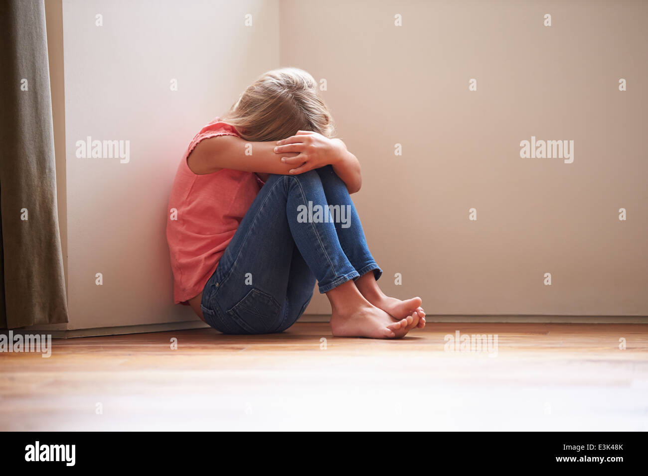 Unglückliches Kind zu Hause auf Boden In der Ecke sitzen Stockfoto