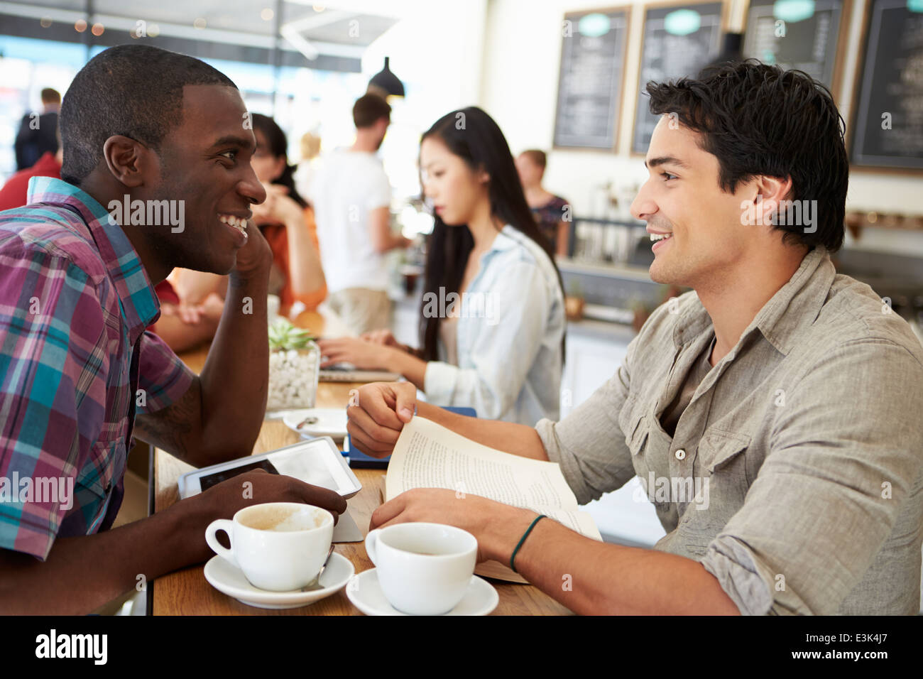 Zwei männliche Freunde treffen In belebten Café Stockfoto