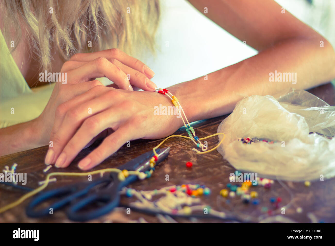 Frau Hände machen Handwerk Handwerk Hobby Armband bunte Perlen Seil Stockfoto