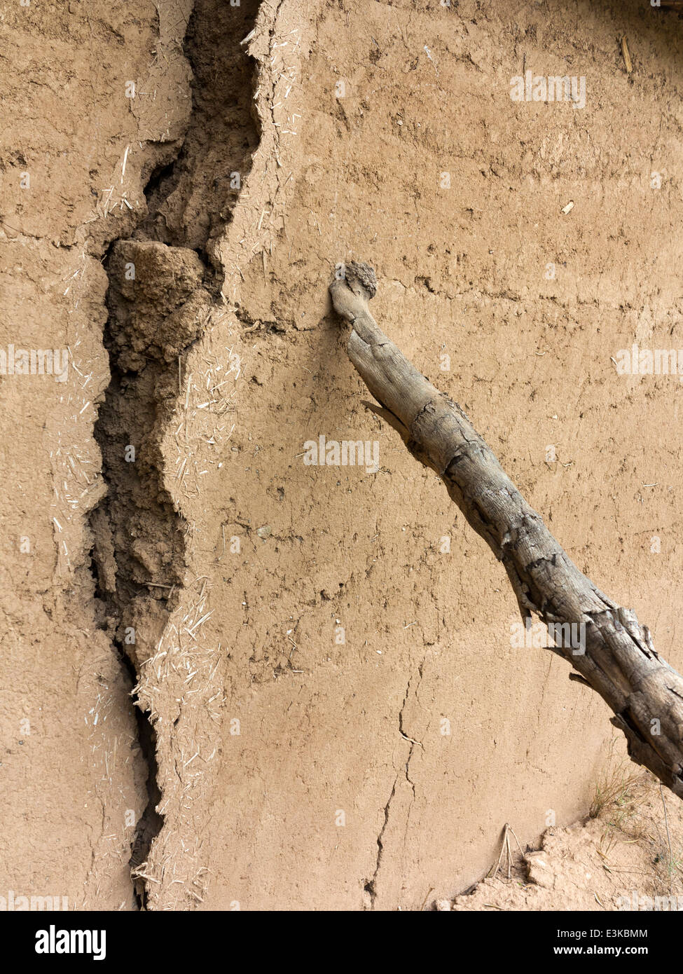 Eine rissige und Neigung Abschnitt der Lehmziegel-Mauer wird unterstützt durch eine hölzerne Stütze Stockfoto