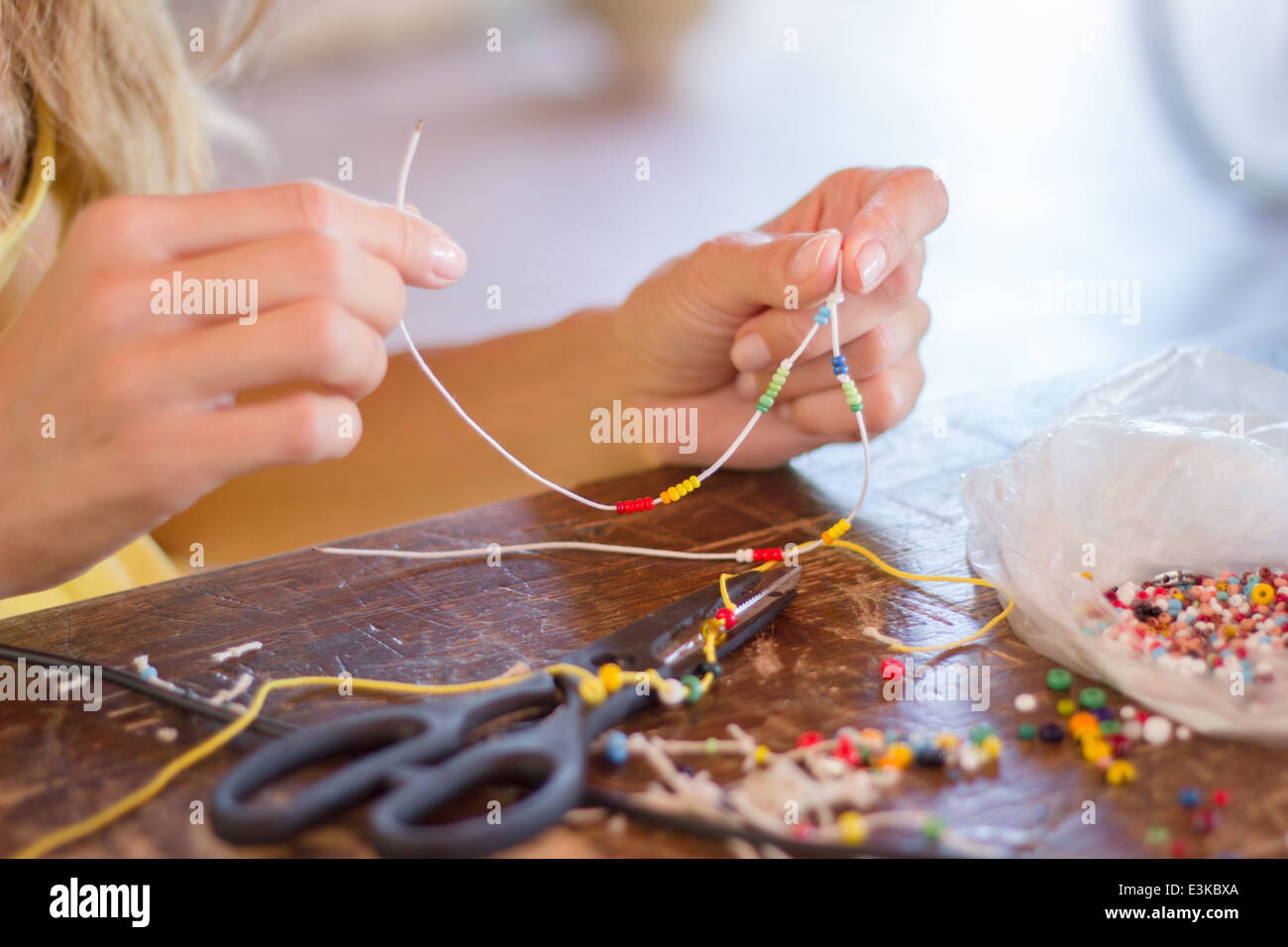 Frau Sicke Hände machen Handwerk Handwerk Hobby Armband bunte Perlen Seil Stockfoto