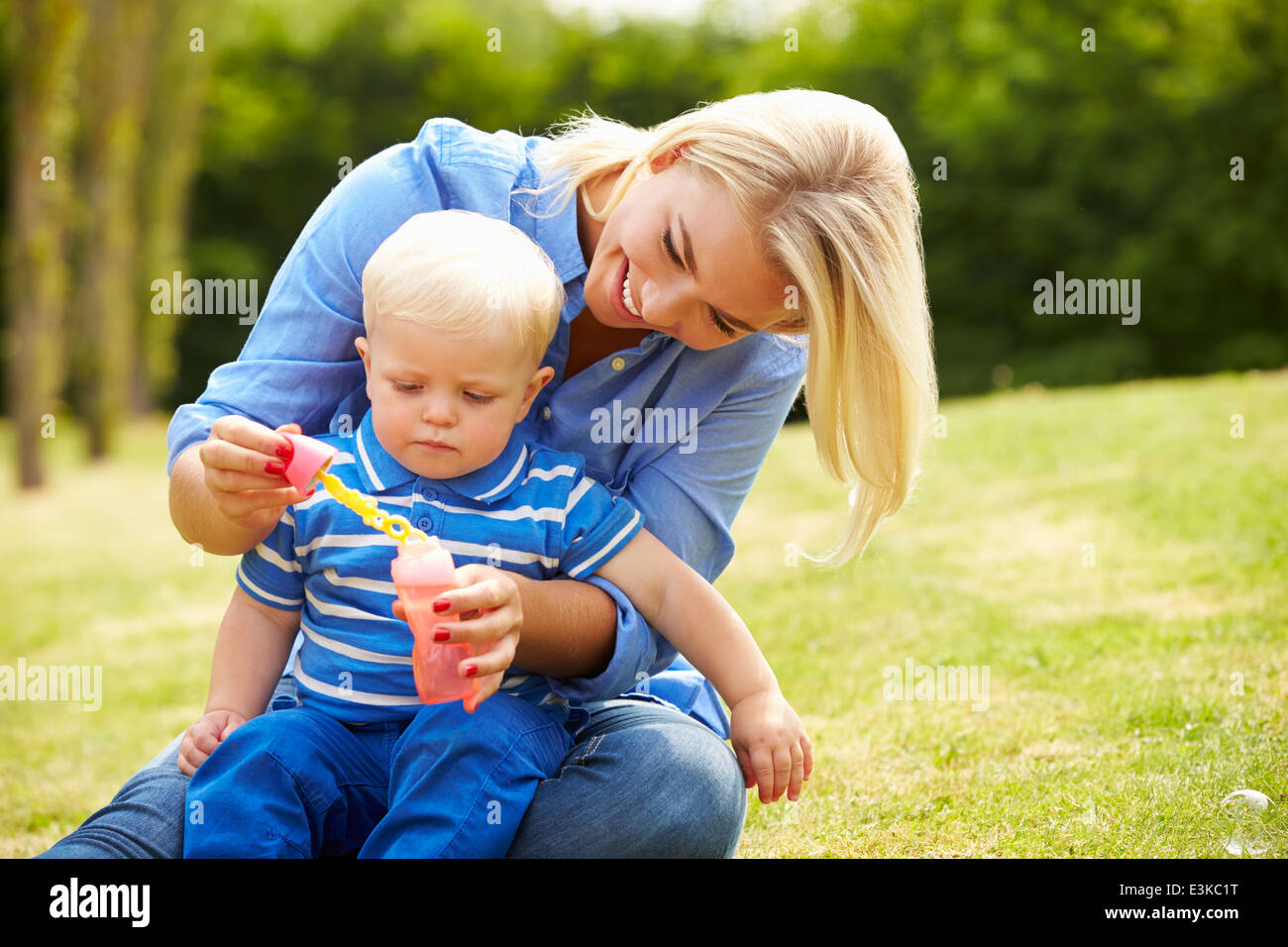 Mutter bläst Seifenblasen für Jungen im Garten Stockfoto