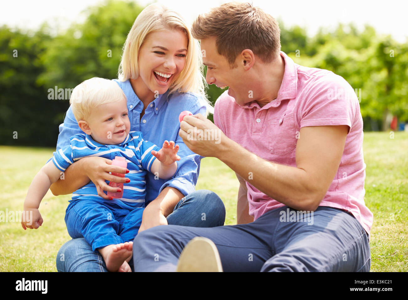 Eltern, die Seifenblasen für Jungen im Garten Stockfoto