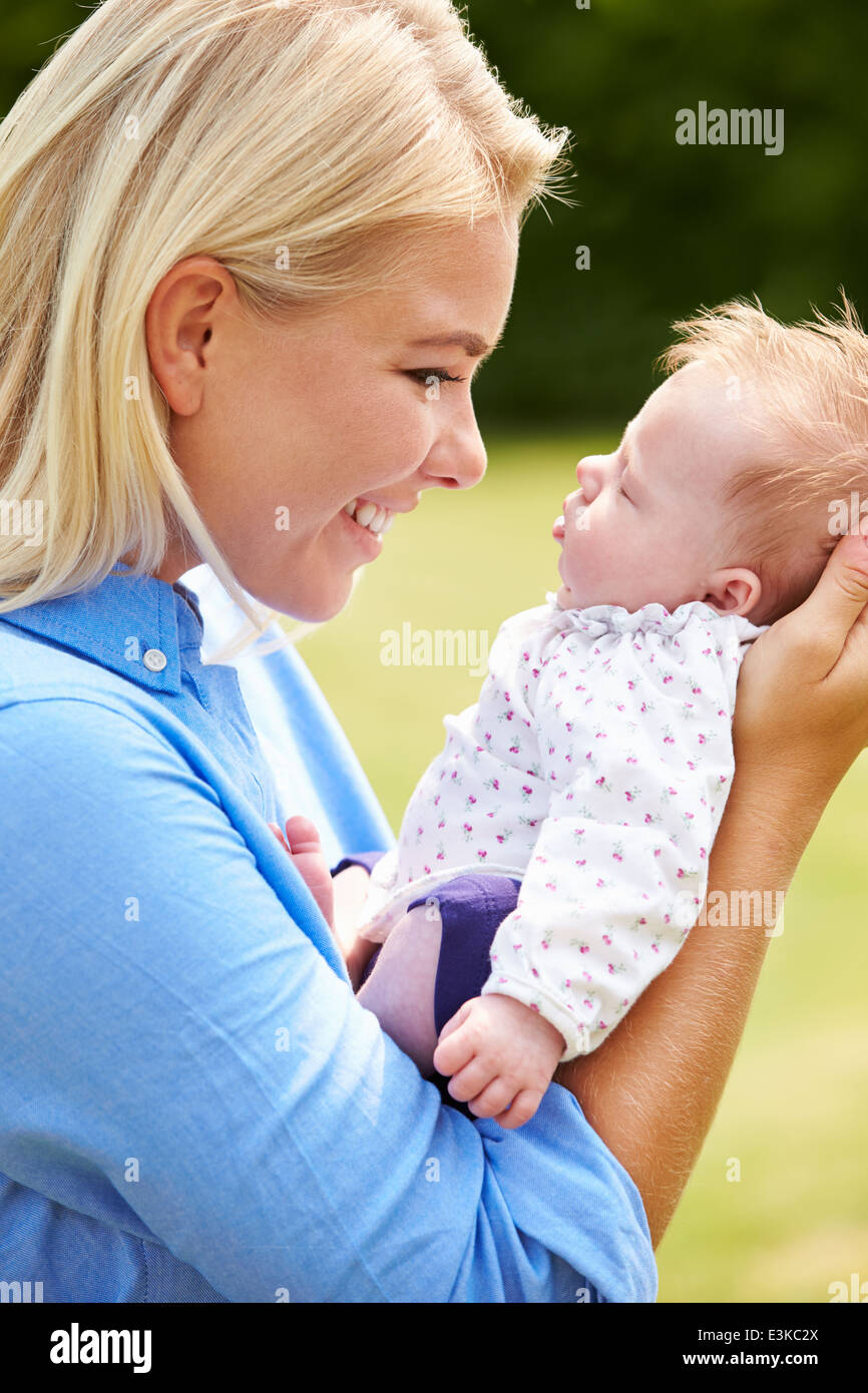 Liebevolle Mutter Holding Baby-Tochter im Garten Stockfoto
