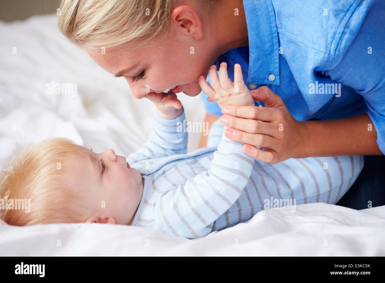 Mutter mit Baby Sohn zu spielen, als sie zusammen im Bett liegen Stockfoto