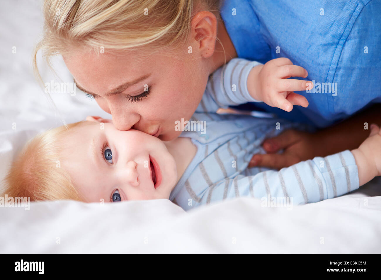 Küssen Baby Sohn Mutter, als sie zusammen im Bett liegen Stockfoto