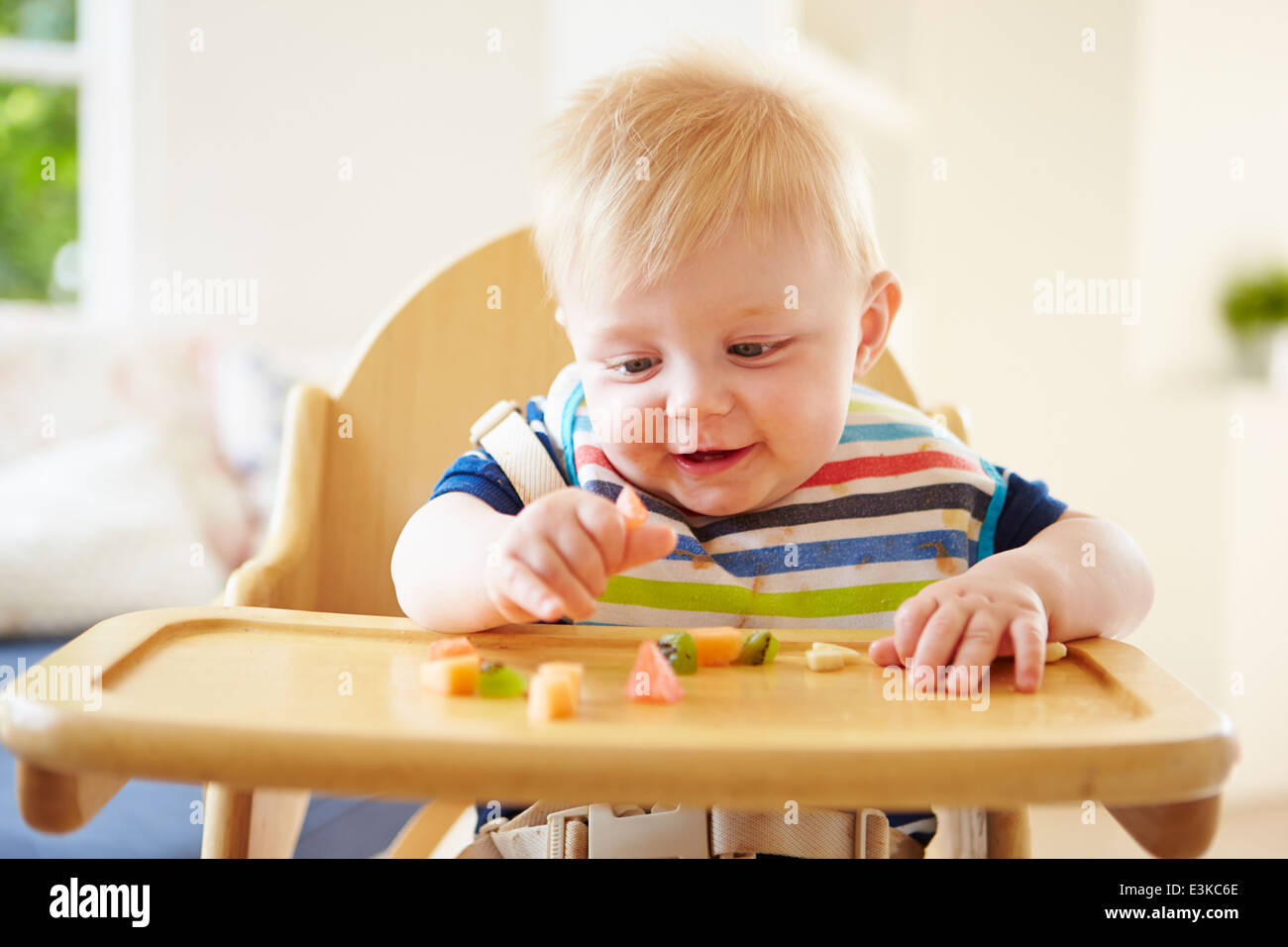 Baby Boy Verzehr von Obst im Hochstuhl Stockfoto