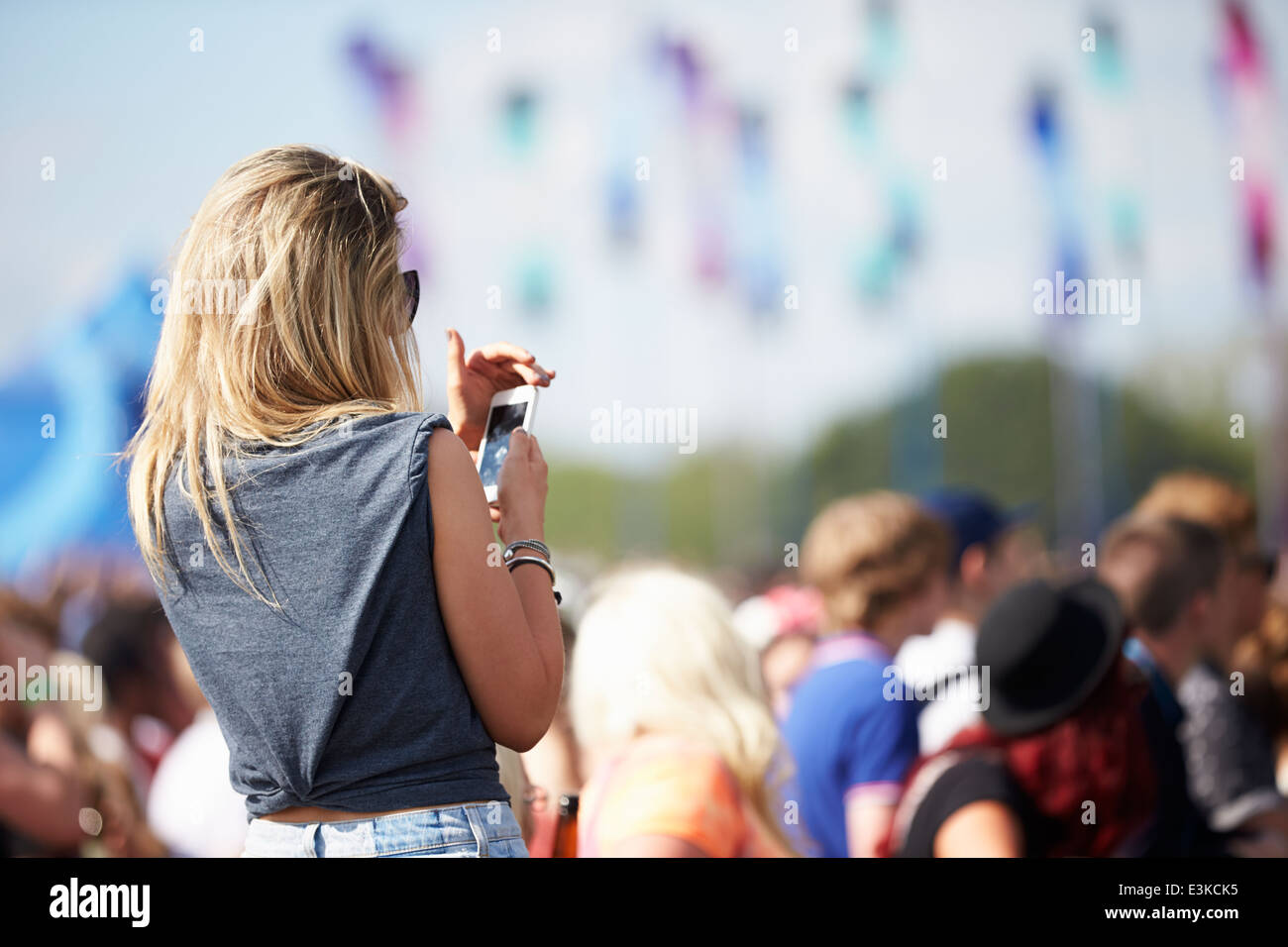 Junge Frau beim Outdoor-Musikfestival mit Handy Stockfoto