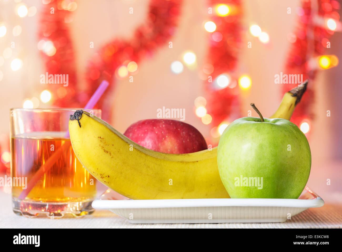 Banane, grüne und rote Äpfel auf weißen Teller und Glas Apfelsaft (Geburtstagsfeier) Stockfoto