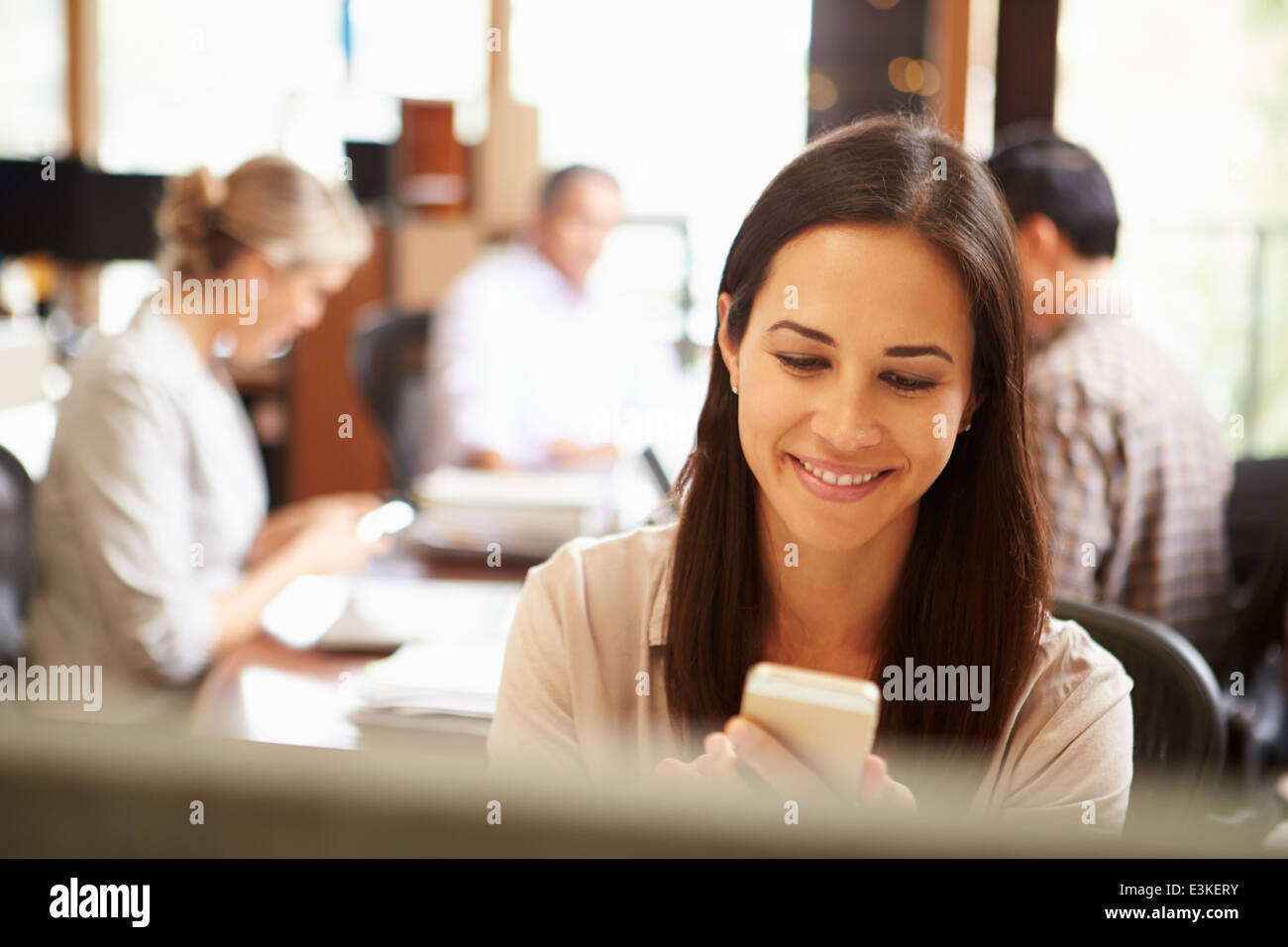 Geschäftsfrau, die Arbeiten am Schreibtisch mit Handy Stockfoto