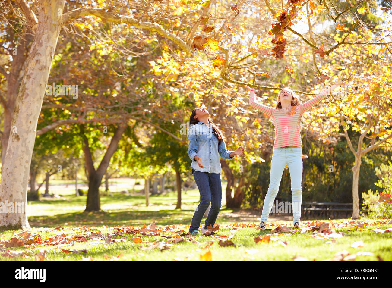 Zwei Mädchen, die Blätter im Herbst In die Luft werfen Stockfoto