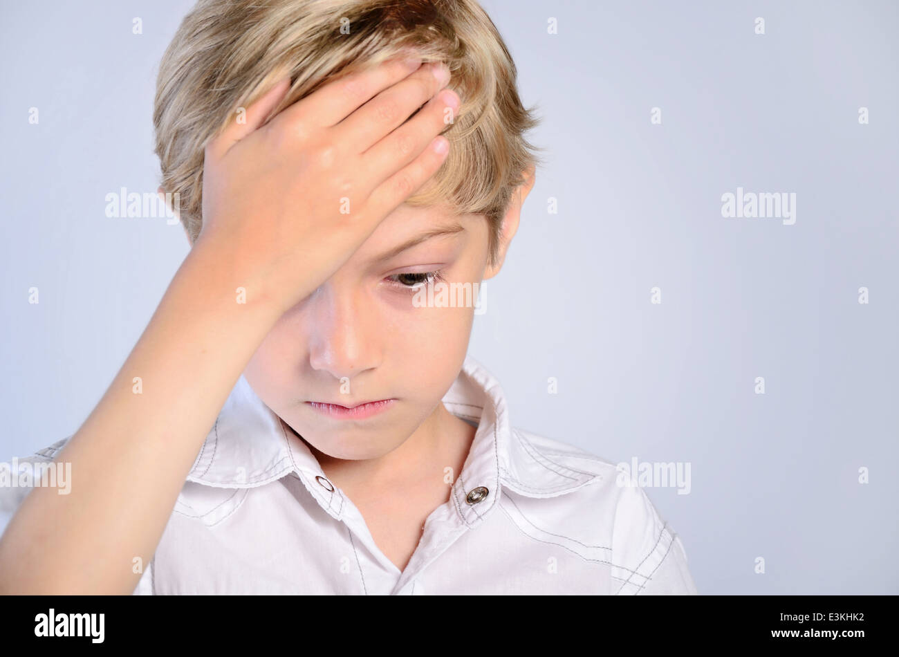 Schmerzen Kopfschmerzen junge Kind Hand Kopf Menschen Porträt Schmerzen krank Hintergrund Stress traurig schön grau grau enttäuscht Kindheit verletzt Stockfoto