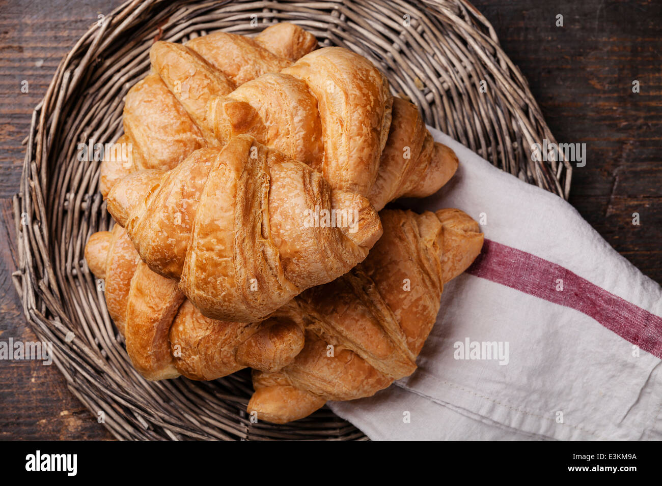 Croissants in Wicker Tablett auf dunklem Holz Stockfoto