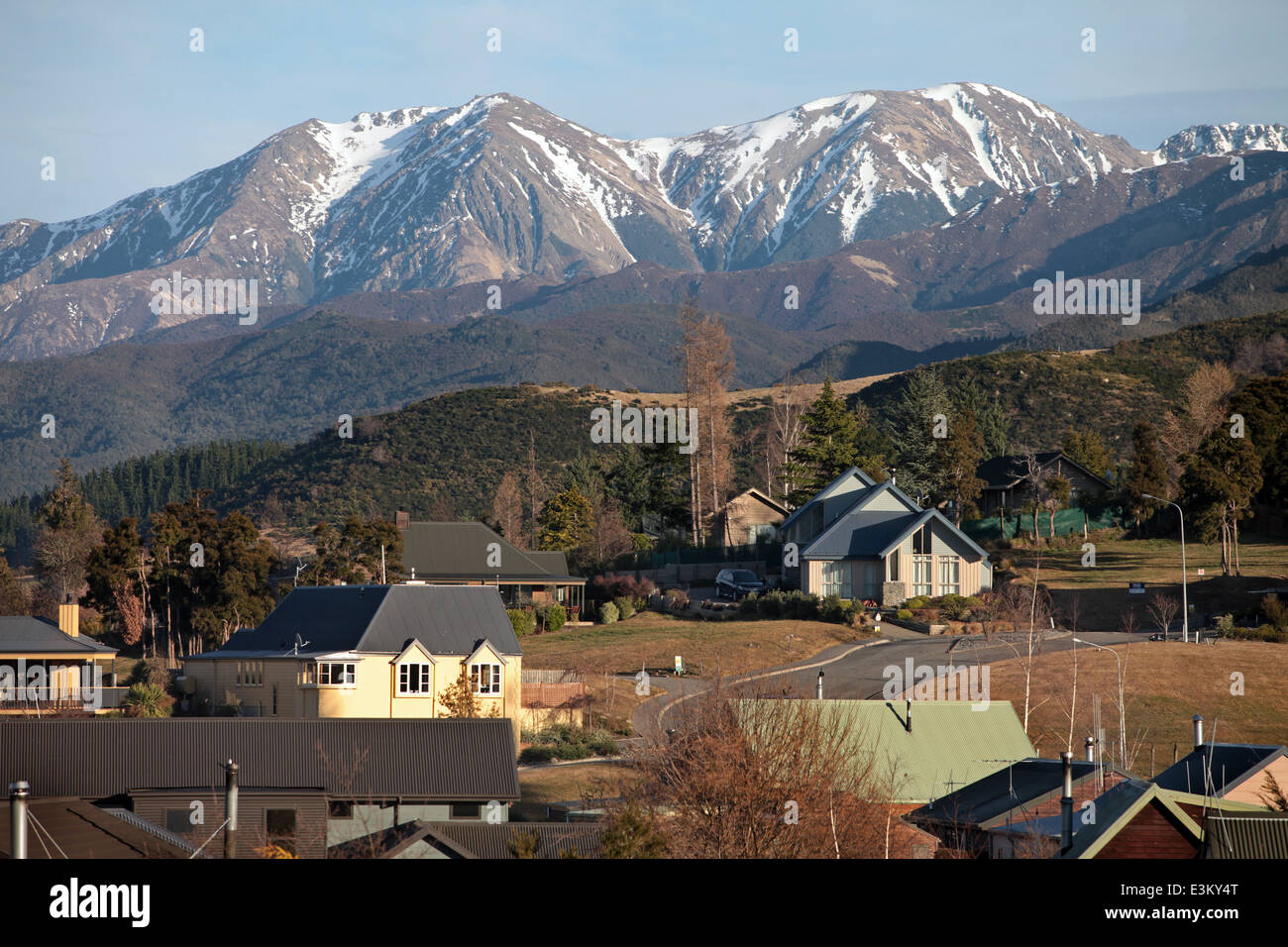 Schneebedeckte Berge hinter Häusern in Hanmer Springs, Neuseeland Stockfoto